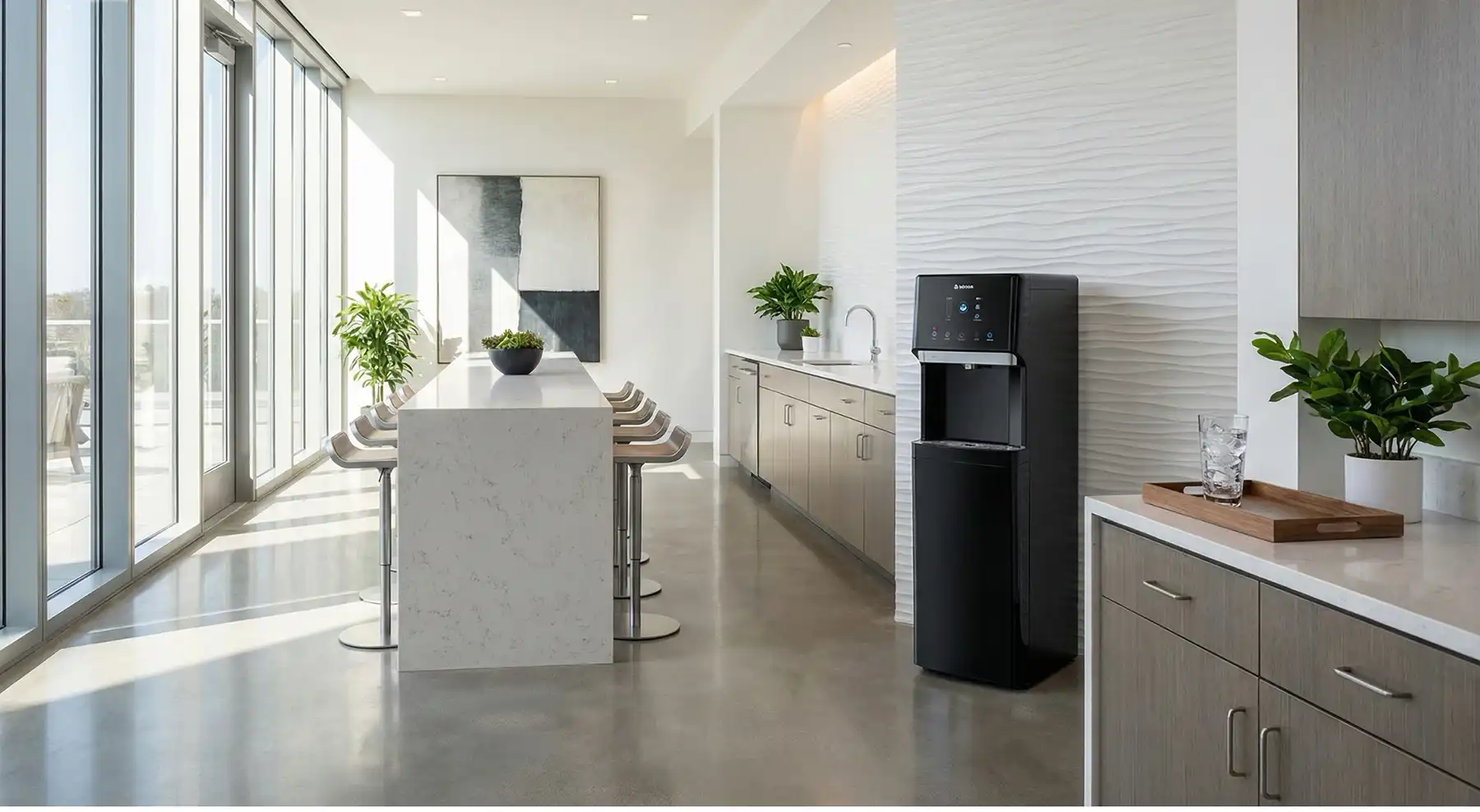 Bright, modern kitchen with a long white marble island, bar stools, and a tall glass wall on the left; sunlight fills the room. - Bishop Business